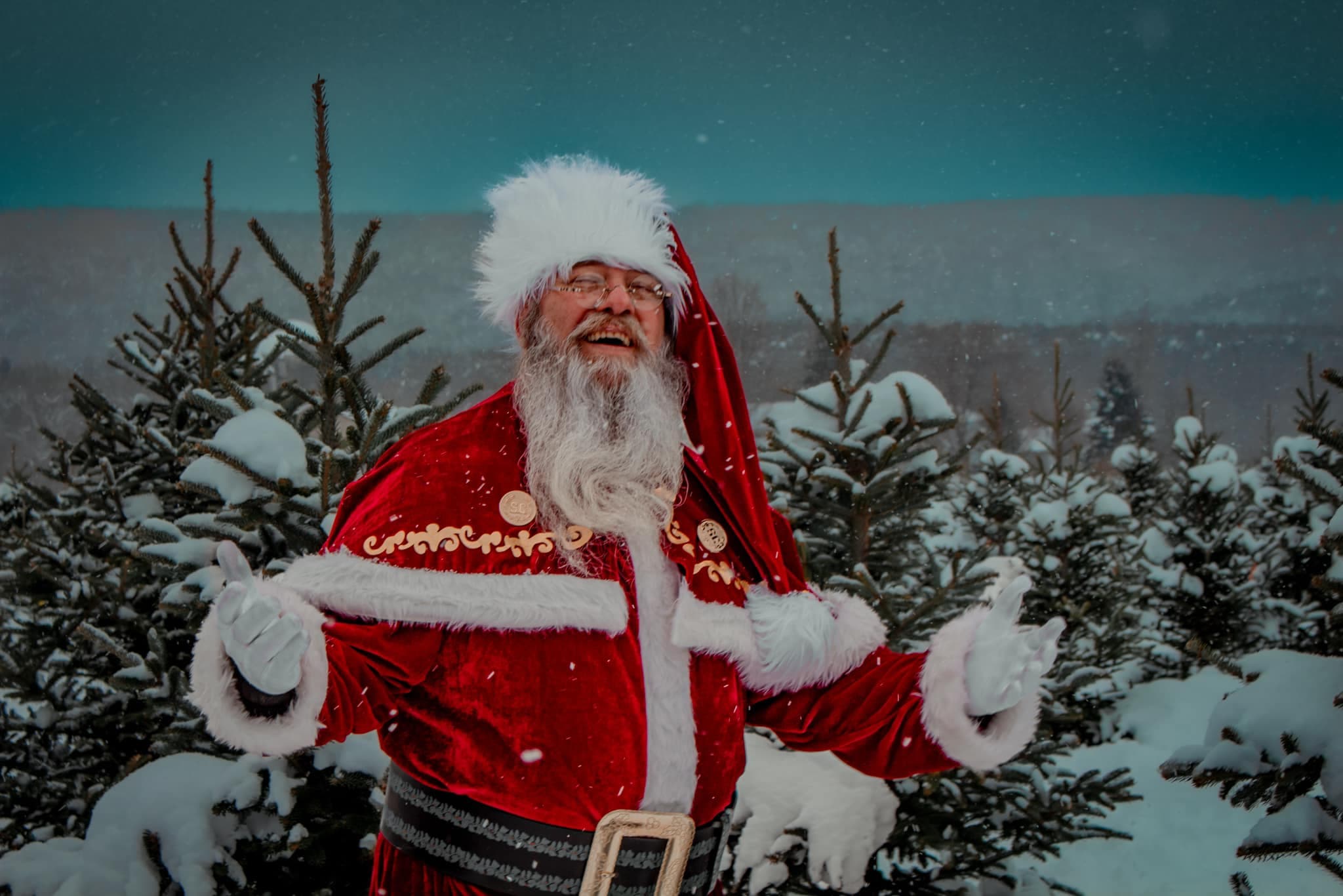 Santa James greeting families in a snow covered evergreen grove
